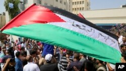 FILE - Palestinian refugees hold flags as they chant slogans during a protest in front in Amman, Jordan, Sept. 2, 2018. 