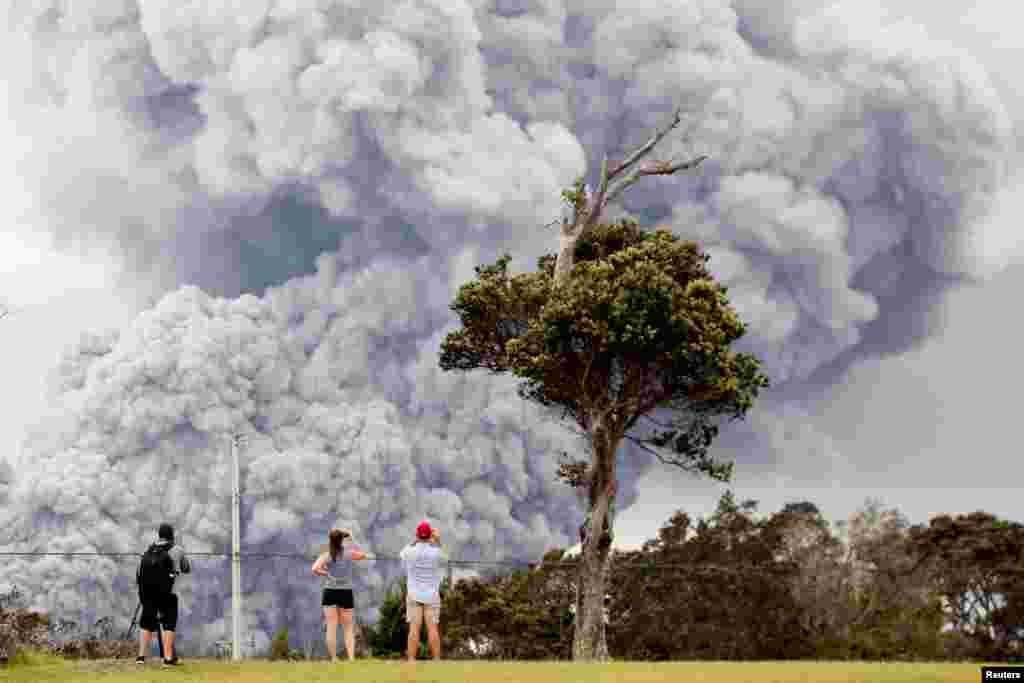 People watch as ash erupts from the Halemaumau crater during ongoing eruptions of the Kilauea Volcano in Hawaii, May 15, 2018.