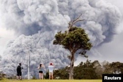 People watch as ash erupts from the Halemaumau crater near the community of Volcano during ongoing eruptions of the Kilauea Volcano in Hawaii, U.S., May 15, 2018.