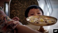 FILE - A North Korean boy peeps over his serving of noodles at a restaurant in Pyongyang, Sept. 1, 2014.