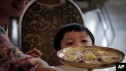 FILE - A young North Korean boy peeps over his serving of noodles at a restaurant in Pyongyang, Sept. 1, 2014.