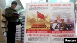 (FILE) A man looks at anti-Falun Gong books for sale in a bookstore, near a poster denouncing the banned spiritual movement in Beijing.