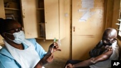 FILE - A man prepares to receive a jab of the AstraZeneca COVID-19 vaccine, at Ndirande Health Centre in Blantyre, Malawi, March 29, 2021.