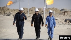 Des travailleurs irakiens marchent dans le champ pétrolifère de West Qurna, dans la province de Bassorah, en Irak, le 28 novembre 2010.