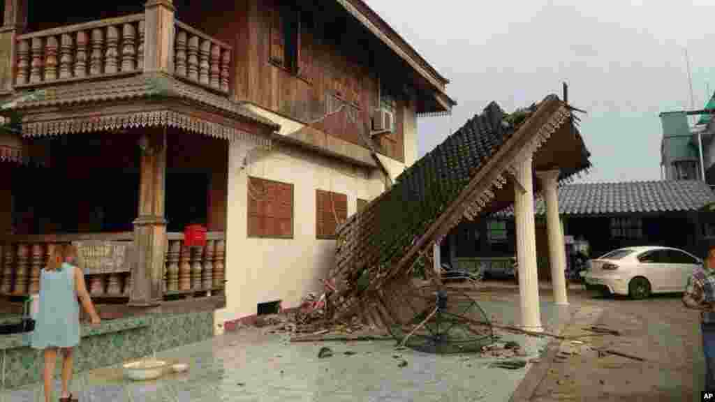 Seorang perempuan mengamati rumah yang rusak akibat gempa bumi di Chiang Rai, Thailand utara, 5 Mei 2014.