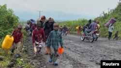 FILE: Civilians carry their belongings as they flee after heavy gunfire that raised fears of M23 rebels advancing along a road from Sake near Goma in the North Kivu province of the Democratic Republic of Congo February 9, 2023.
