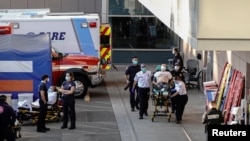 Paramedics escort a patient from the ambulance entrance to the emergency room at LAC + USC Medical Center during a surge of coronavirus disease (COVID-19) cases in Los Angeles, California, Dec. 27, 2020. 