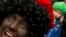 FILE: A "Black Pete" interacts with children during the arrival of Sinterklaas in Maassluis, Netherlands, Saturday, Nov. 12, 2016. "Black Pete" is often played by white people with their faces daubed in dark makeup.Netherlands Black Pete Protest