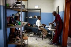 Technicians Cereste Cherisme, right, and Jules Emmanuel, chat during their shift at the workshop in St. Vincent's Center in Port-au-Prince, May 22, 2019.