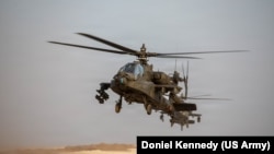 资料照片：2025年11月4日，隶属于美国陆军第4战斗航空旅第17空骑团第6中队“夜鹰”特遣队的两架AH-64阿帕奇直升机在美国中央司令部责任区内执行航空作战任务时飞越着陆区。