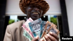 Raia wa Sudan Kusini akishikilia fedha inayotumika nchini humo.