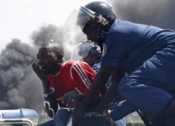 A riot police officer sprays teargas on residents participating in street protests against the decision made by Burundi's ruling party to allow President Pierre Nkurunziza to run for a third five-year term, in the capital Bujumbura, April 26, 2015.