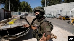 An Israeli soldier from an EOD (explosive ordnance disposal) unit gestures next to Iranian ballistic missile components that were fired at Israel, during a government-organized media tour on a base in southern Israel, Oct. 9, 2024.