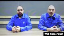 A web page on the website of the Russian news agency RIA Novosty identifies the man sitting at the right as Maxim Shugaley, and the man on the left as Samer Sueifan. There is no description of where and when the photo was taken.