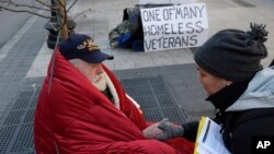 FILE - A homeless Korean War veteran speaks with an outreach coordinator on a sidewalk in Boston, Massachusetts, Nov. 20, 2013.