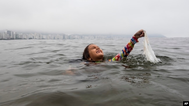 Nina Gomez duke nxjerrë një qese plastike nga deti pranë Rio de Janeiros, Brazil