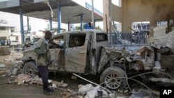 Seorang petugas keamanan Somalia memperhatikan mobil yang rusak dekat hotel Nasa-Hablod di Mogadishu, Somalia, 26 Juni 2016. 