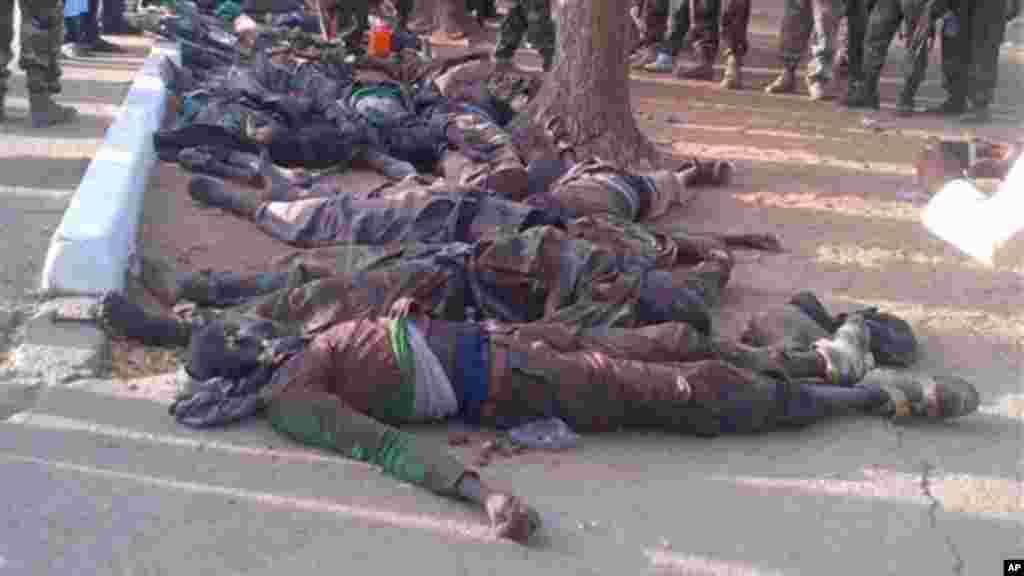 In this photo taken with a mobile phone, Tuesday, May. 7, 2013, soldiers looks at bodies of suspected Islamic extremist killed during heavy fighting in Bama, Nigeria.