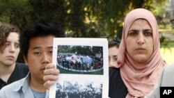 FILE - Ian Lee (l) and Fatima Sbeih (r) two of the students pepper-sprayed at the University of California, Davis, November 2011, are seen behind photos of the incident displayed during a news conference where the terms of a lawsuit settlement was discussed at UC Davis in Davis, Calif., Sept. 26, 2012.