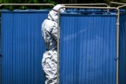 A health official wearing protective gear takes a sample from a man sitting in a temporary cabin at the drive-through screening and testing facility for the coronavirus alongside a street in Islamabad, June 3, 2020.