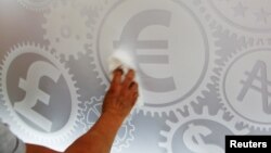 A man cleans a board with different currency signs at a currency exchange office in Madrid, Spain, June 24, 2016. 