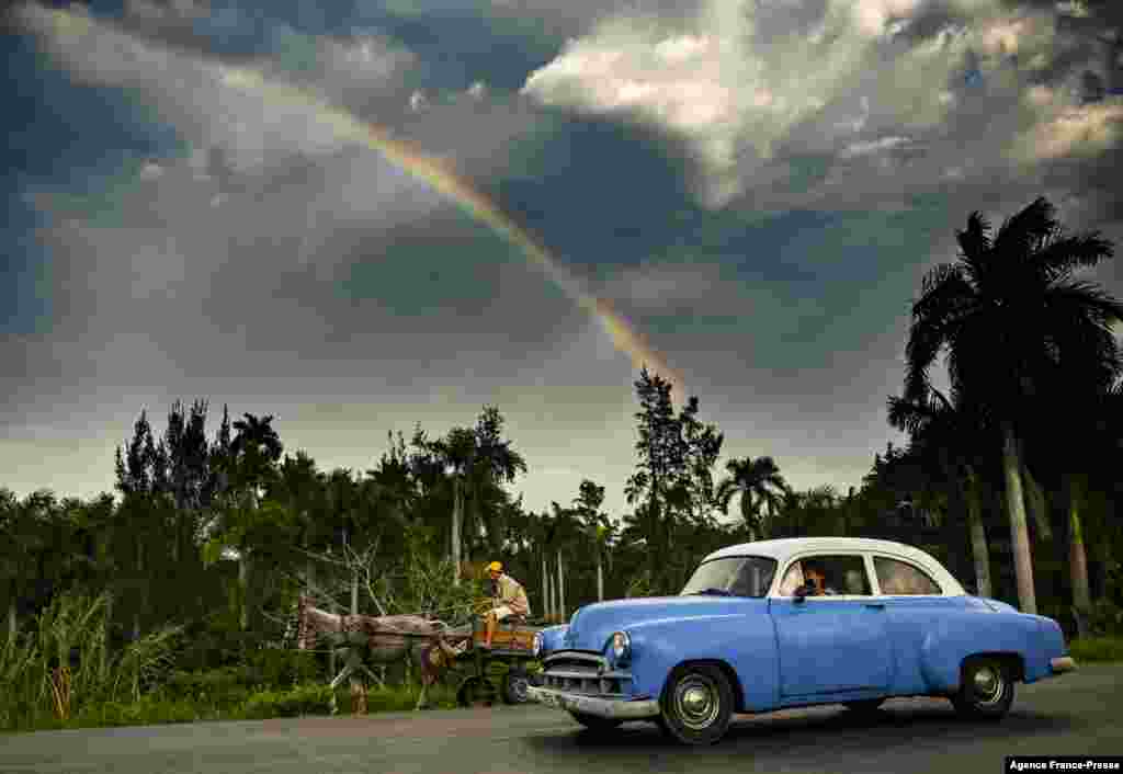 An old American car is seen in Havana, Cuba, as a rainbow appears in the sky.