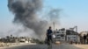 A man cycles as behind smoke from Israeli bombardment rises in an area that was ordered to be evacuated by the Israeli army in the southeast of Khan Yunis in the southern Gaza Strip, Sept. 8, 2024.