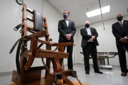 فرماندار ویرجینیا در کنار یک صندلی الکتریکی که از آن برای مجرمان محکوم به اعدام استفاده می‌شد.