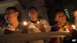 Tibetan exiles hold ceremonial scarves tied together as they participate in a candlelit vigil after reports of another self-immolation in Tibet, in Dharmsala, India, Oct. 5, 2012.