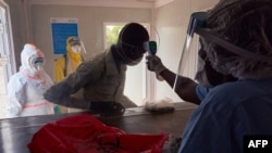 FILE - A suspected COVID-19 patient's temperature is measured as he is admitted at the isolation ward of Ministry of Health Infectious Disease Unit in Juba, South Sudan, April 24, 2020.