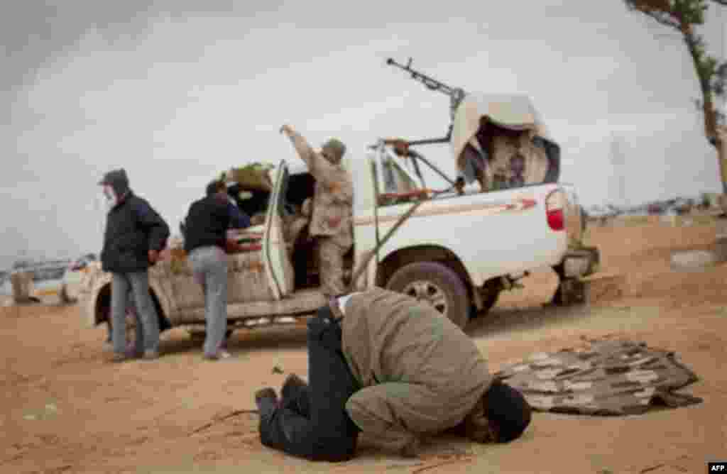 A Libyan rebel prays on the frontline on the outskirts of the city of Ajdabiya, south of Benghazi, eastern Libya, Monday, March 21, 2011. The international military intervention in Libya is likely to last "a while," a top French official said Monday, echo