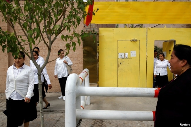 FILE - Ethnic Uyghur women leave a center where political education lessons are held in Kashgar, in Xinjiang Uyghur Autonomous Region, China, Sept. 6, 2018.