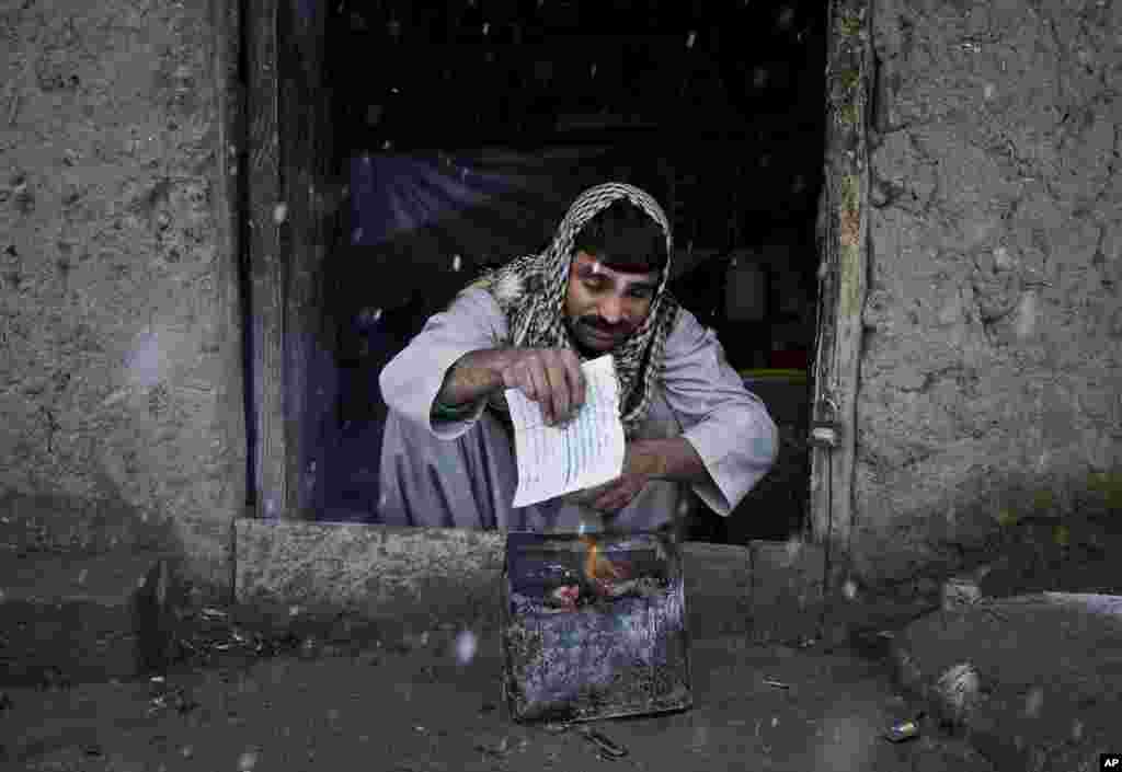 2012年12月27日，一位失去家园在阿富汗国内逃难的男子在喀布尔一处难民营生火取暖。