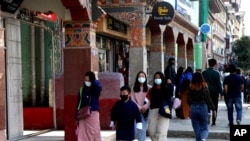 Bhutanese people wearing face masks walk through a street in Thimpu, Bhutan, as the tiny Himalayan kingdom wedged between India and China has vaccinated nearly 93% of its adult population since March 27.