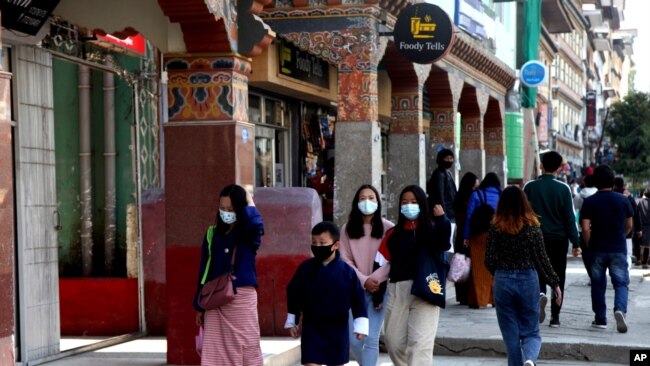 Bhutanese people wearing face masks as precaution against coronavirus walk through a street in Thimpu, Bhutan, Monday, April 12, 2021. The tiny Himalayan kingdom is wedged between India and China.
