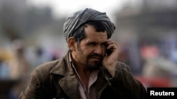 FILE - An Afghan man talks on his mobile phone on a street in Kabul, March 24, 2011. Taliban insurgents recently shut down private telecommunication companies in several parts of the country.