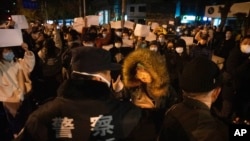 北京警方面对不满新冠封控措施而在街上举白纸抗议的民众（2022年11月27日）