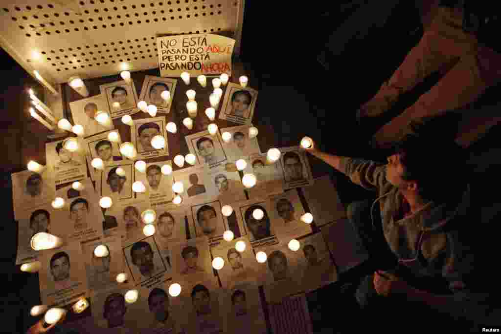 People light candles around the photographs of missing students from the Ayotzinapa teachers' training college during a protest at the Monterrey Institute of Technology in Monterrey, Oct. 23, 2014.
