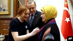 FILE - U.S. actress Lindsay Lohan, left, places a badge bearing a quote from Turkey's President Recep Tayyip Erdogan, center, reading "World is bigger than five," referring to the UN Security Council's five permanent members.