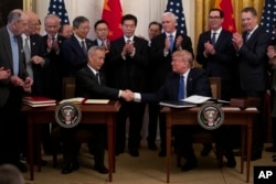 FILE - President Donald Trump and Chinese Vice Premier Liu He shingle  hands aft  signing "phase one" of a U.S. - China commercialized   agreement, successful  the East Room of the White House, Jan. 15, 2020, successful  Washington.