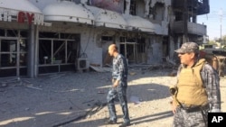 Iraqi security forces inspect one of the damaged buildings after clashes between Iraqi security forces and members of the Islamic state in the city of Kirkuk, 180 miles (290 kilometers) north of Baghdad, Iraq, Oct, 22, 2016. 