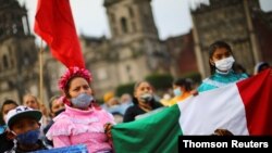 Women hold a Mexican flag as relatives of the 43 missing students of the Ayotzinapa Teacher Training College march on the sixth anniversary of their disappearance in Mexico City, Mexico, Sept. 26, 2020.