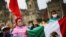 Women hold a Mexican flag as relatives of the 43 missing students of the Ayotzinapa Teacher Training College march on the sixth anniversary of their disappearance in Mexico City, Mexico, Sept. 26, 2020.