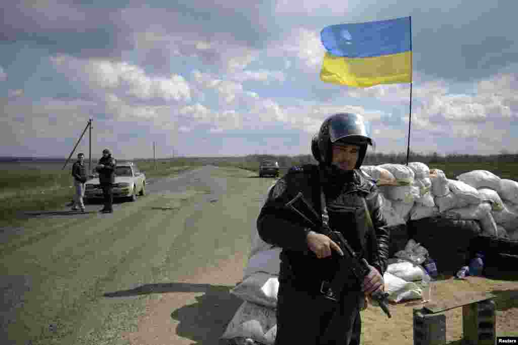 Binh sĩ Ukraine canh gác tại một trạm kiểm soát treo quốc kỳ Ukraine gần thành phố Barvenkovo ​​trong khu vực Kharkiv ở miền đông Ukraine, ngày 15/4/2014.