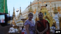 A western tourist poses for a photograph with a Buddhist monk at the Shwedagon Pagoda in Rangoon, Burma, May 31, 2012.