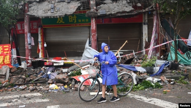 Seorang warga membawa sepedanya di antara rumah yang rusak akibat gempa di Luzhou, provinsi Sichuan, China, Kamis 16 September 2021.