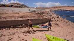 Visitors carry a kayak up a newly exposed cliff face beneath the closed Antelope Point launch ramp on Lake Powell, July 31, 2021, near Page, Ariz.