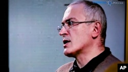 FILE - Mikhail Khodorkovsky, once Russia's richest man, speaks during a webcast conference in London, and is seen on a TV screen in Open Russia movement office in Moscow, Dec. 9, 2015.