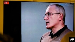 Mikhail Khodorkovsky, once Russia's richest man, speaks during a webcast conference in London, and is seen on a TV screen in Open Russia movement office in Moscow, Dec. 9, 2015.