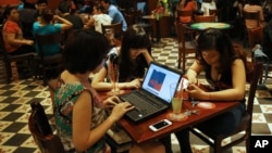 Three young Vietnamese girls use a laptop and smart phones to go online at a cafe in Ha Noi, Vietnam, May 14, 2013. 